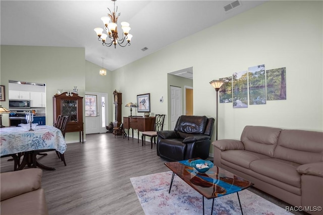 living room featuring wood-type flooring, high vaulted ceiling, and a chandelier