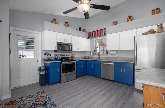 kitchen with blue cabinetry, sink, white cabinetry, vaulted ceiling, and appliances with stainless steel finishes