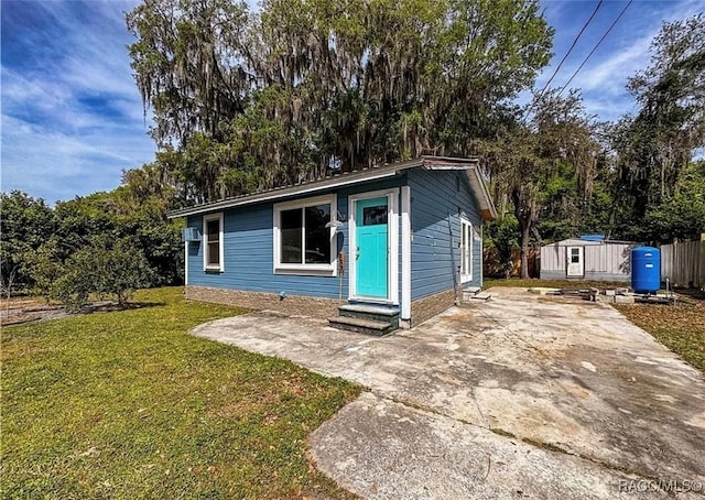 exterior space featuring a storage shed, a front lawn, and a patio area