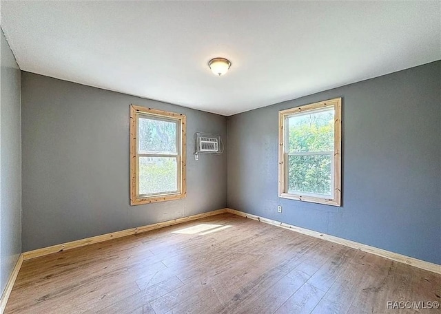 empty room featuring an AC wall unit and light wood-type flooring