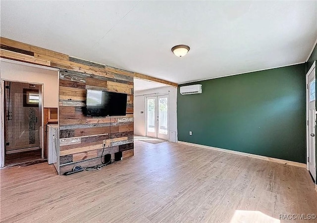 living room featuring french doors, wooden walls, an AC wall unit, and light wood-type flooring