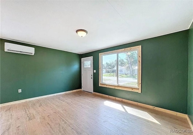 empty room featuring a wall mounted air conditioner and light hardwood / wood-style flooring