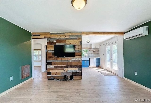 living room featuring wood walls, beam ceiling, a wall unit AC, and light wood-type flooring