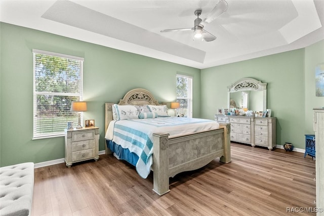 bedroom featuring hardwood / wood-style flooring, a raised ceiling, and ceiling fan