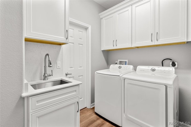 washroom featuring cabinets, light wood-type flooring, sink, and washing machine and clothes dryer