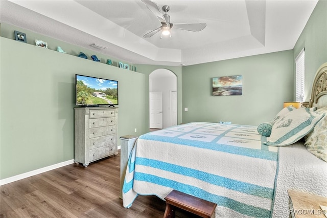 bedroom with hardwood / wood-style flooring, ceiling fan, and a tray ceiling