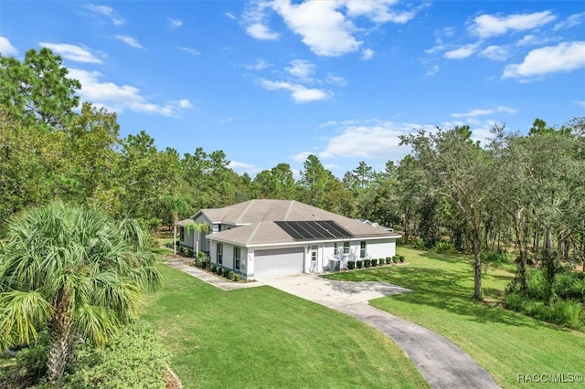 view of front of property featuring a garage, a front yard, and solar panels