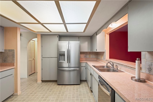 kitchen featuring gray cabinets, tasteful backsplash, appliances with stainless steel finishes, and sink