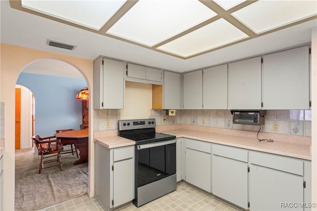 kitchen with stainless steel electric stove, gray cabinets, and backsplash