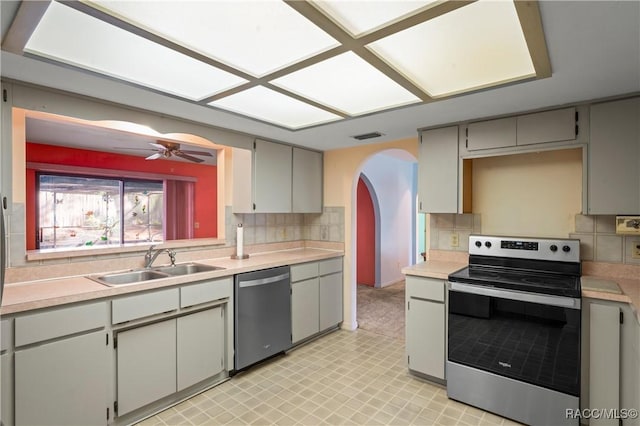 kitchen featuring sink, gray cabinetry, backsplash, ceiling fan, and stainless steel appliances