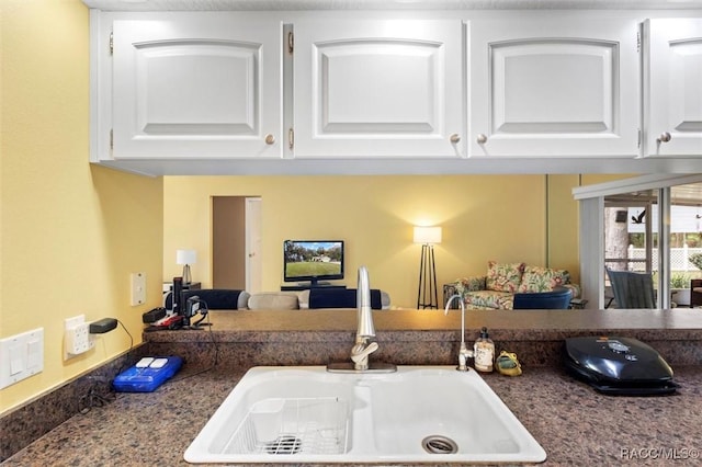 interior details featuring dark countertops, a sink, and white cabinets