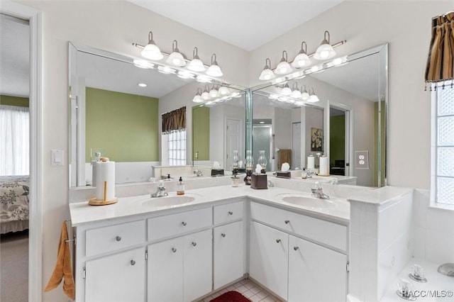 ensuite bathroom featuring a sink, double vanity, connected bathroom, and tile patterned floors