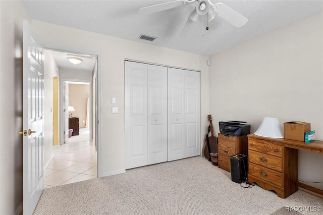 office space with light tile patterned floors, light colored carpet, visible vents, a ceiling fan, and baseboards