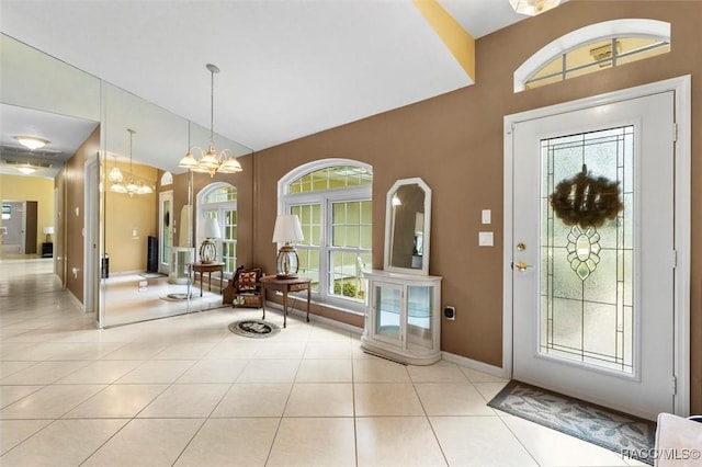 entrance foyer featuring a chandelier, lofted ceiling, baseboards, and tile patterned floors