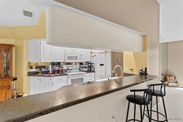 kitchen featuring white appliances, visible vents, dark countertops, white cabinetry, and a sink