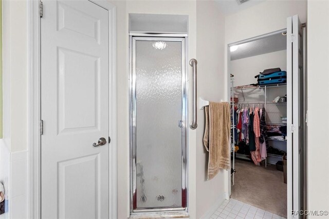 full bathroom with a walk in closet and a shower stall