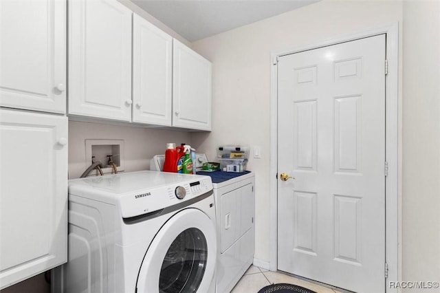 laundry room with washer and clothes dryer, light tile patterned flooring, and cabinet space