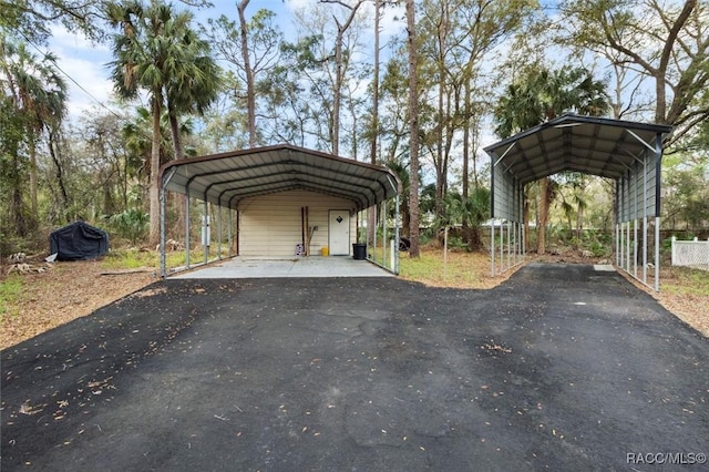 view of car parking with driveway, fence, and a detached carport