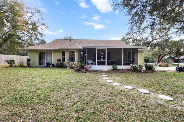 ranch-style home with a front yard, fence, a sunroom, and stucco siding