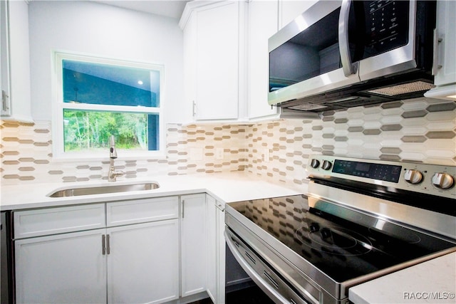 kitchen featuring decorative backsplash, sink, white cabinetry, and stainless steel appliances