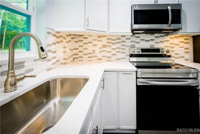 kitchen with white cabinets, backsplash, sink, and appliances with stainless steel finishes