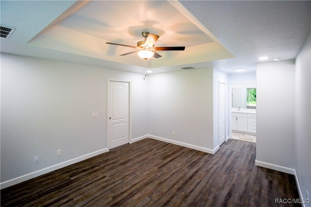 unfurnished room featuring a tray ceiling, ceiling fan, and dark hardwood / wood-style flooring