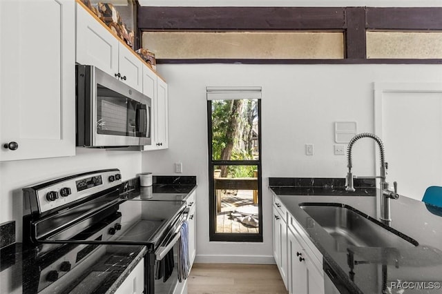 2647 N Seabreeze Pt, Crystal River, FL 34429 - kitchen with white cabinets, a sink, light wood-style flooring, dark stone countertops, and stainless steel appliances