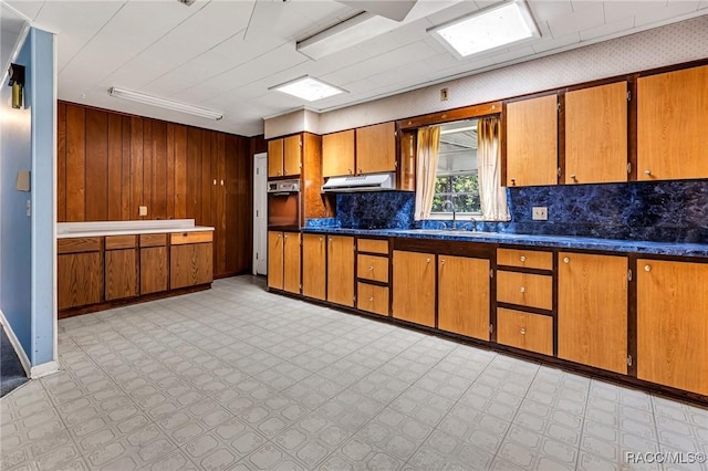 kitchen featuring tasteful backsplash, sink, and wood walls