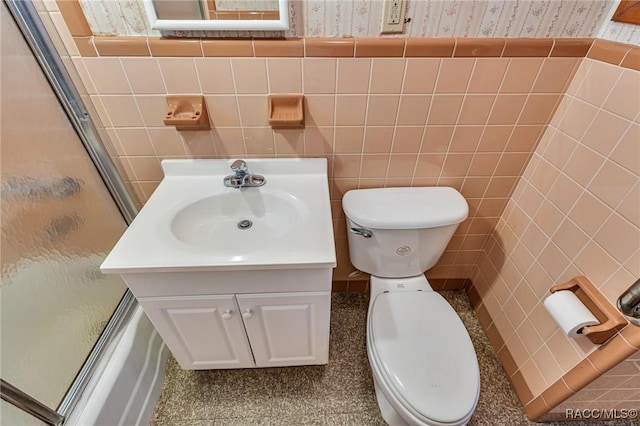 full bathroom with vanity, tile walls, shower / bath combination with glass door, and toilet