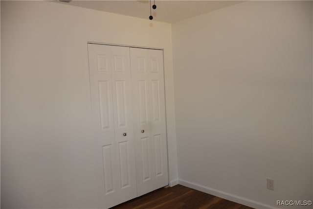 unfurnished bedroom with a closet and dark hardwood / wood-style floors