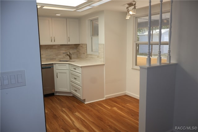 kitchen with hardwood / wood-style floors, dishwasher, sink, decorative backsplash, and white cabinetry