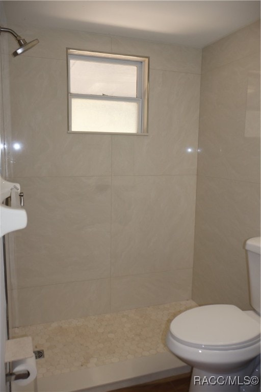 bathroom with a tile shower and toilet