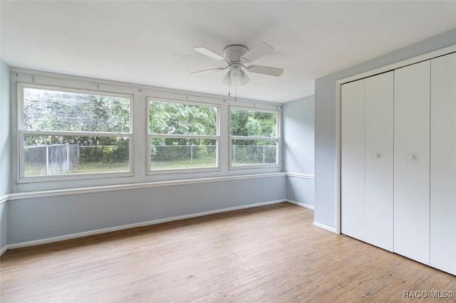 unfurnished bedroom featuring multiple windows, ceiling fan, a closet, and light wood-type flooring