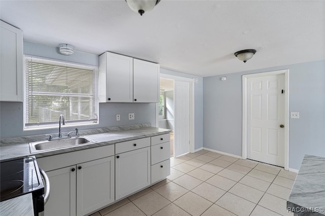 kitchen featuring sink, white cabinets, light tile patterned floors, and range