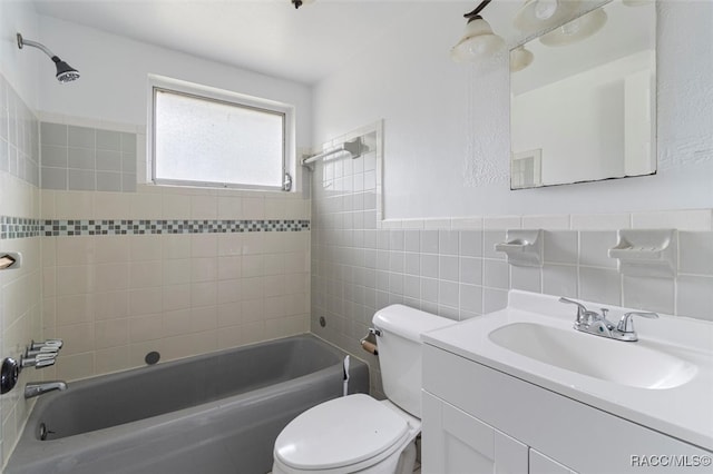 full bathroom with vanity, tiled shower / bath combo, toilet, and tile walls