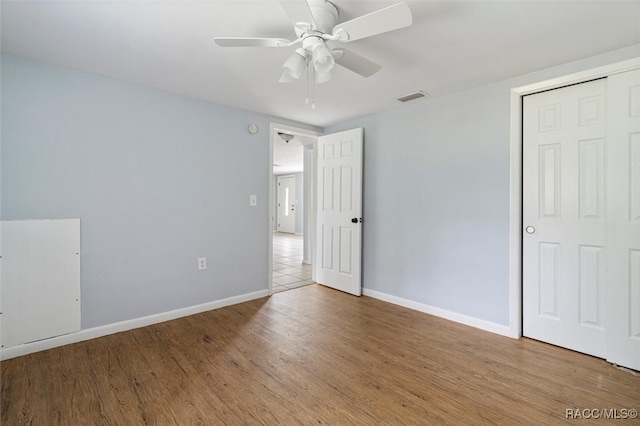 unfurnished bedroom featuring ceiling fan, a closet, and wood-type flooring