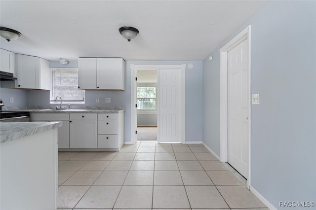 kitchen with light tile patterned floors, sink, white cabinetry, and electric stove