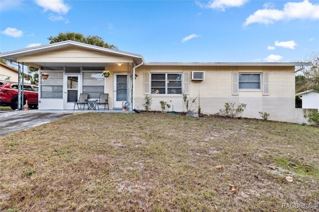 ranch-style house featuring a wall mounted AC and a front lawn