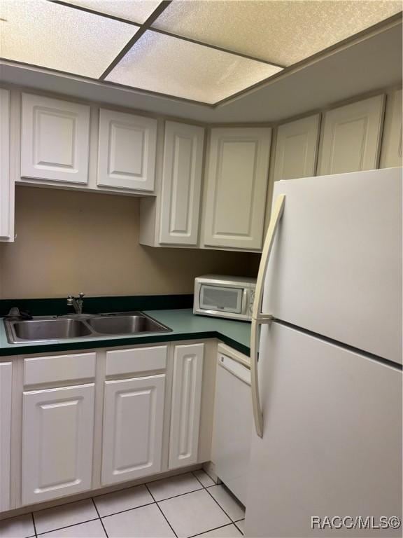 kitchen featuring white cabinetry, sink, white appliances, and light tile patterned floors