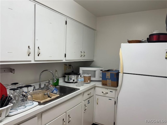 kitchen with sink, white cabinets, and white appliances