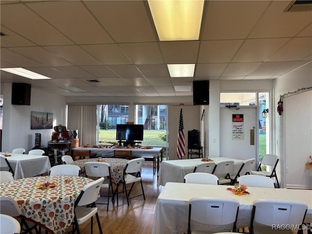 dining room with a paneled ceiling, a healthy amount of sunlight, and hardwood / wood-style floors