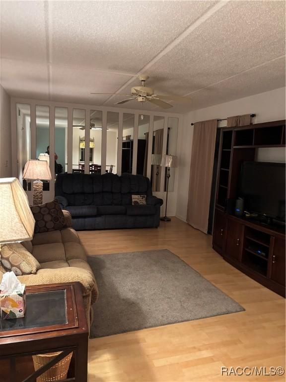 living room with ceiling fan, hardwood / wood-style flooring, and a textured ceiling