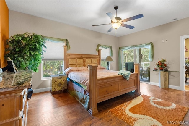 bedroom with dark hardwood / wood-style floors, ceiling fan, and multiple windows