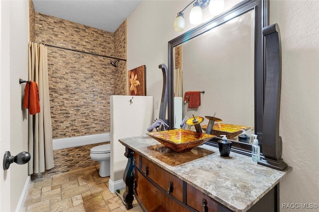 full bathroom with a textured ceiling, vanity, toilet, and shower / bath combo with shower curtain