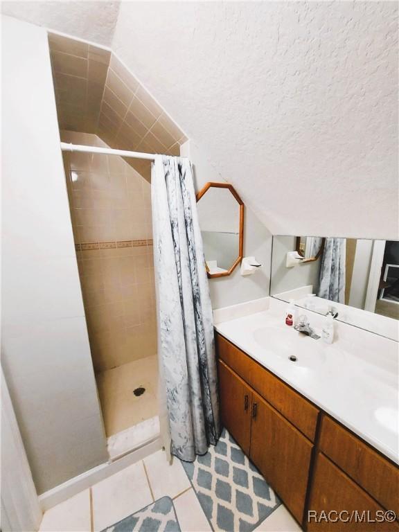 9885 E Lindale Ct, Inverness, FL 34450 - bathroom featuring a shower stall, vanity, tile patterned floors, and lofted ceiling