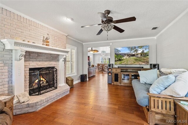 9885 E Lindale Ct, Inverness, FL 34450 - living room with ceiling fan, wood finished floors, ornamental molding, a fireplace, and a textured ceiling