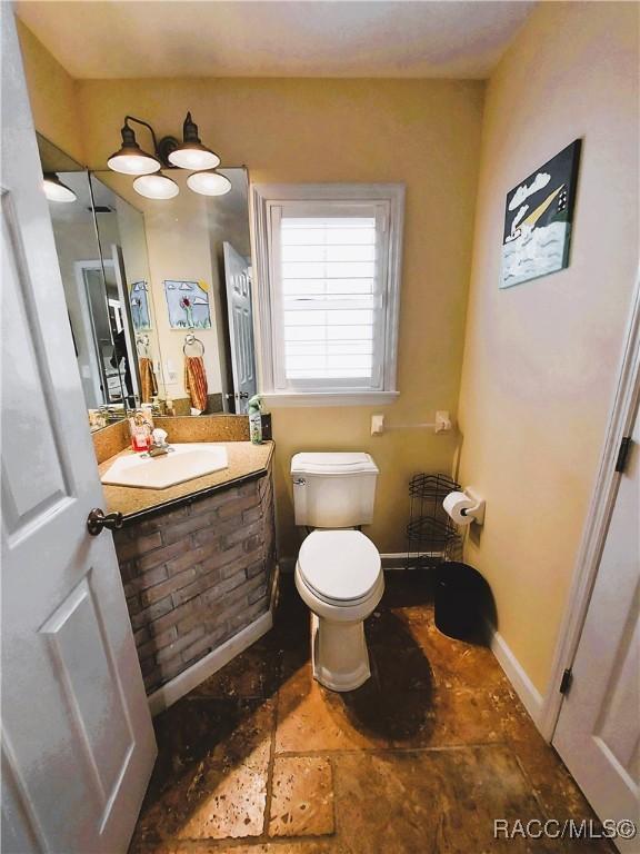 9885 E Lindale Ct, Inverness, FL 34450 - half bath featuring stone finish floors, toilet, and vanity