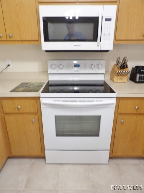 kitchen featuring light tile patterned floors, white appliances, and decorative backsplash