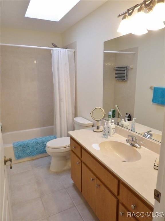 full bathroom featuring shower / tub combo with curtain, a skylight, vanity, toilet, and tile patterned floors