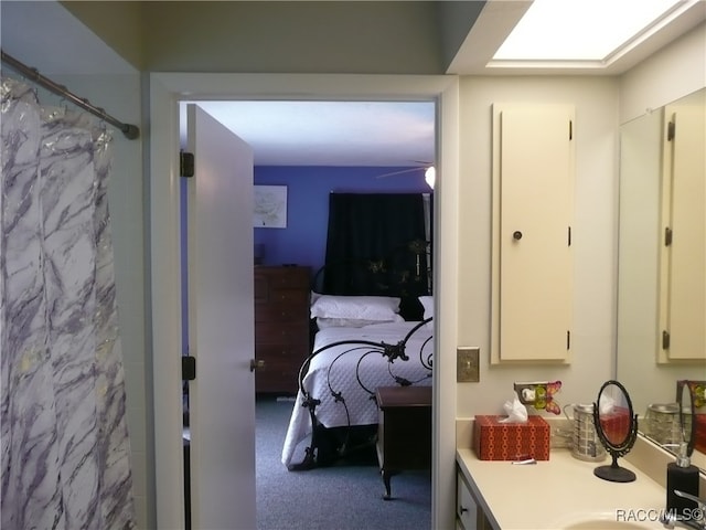 bathroom with a skylight, ceiling fan, vanity, and a shower with shower curtain